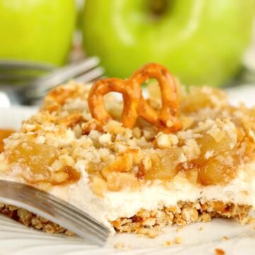 Apple cinnamon pretzel salad topped with a pretzel twist, showing the creamy filling, apple topping, and crunchy crust.