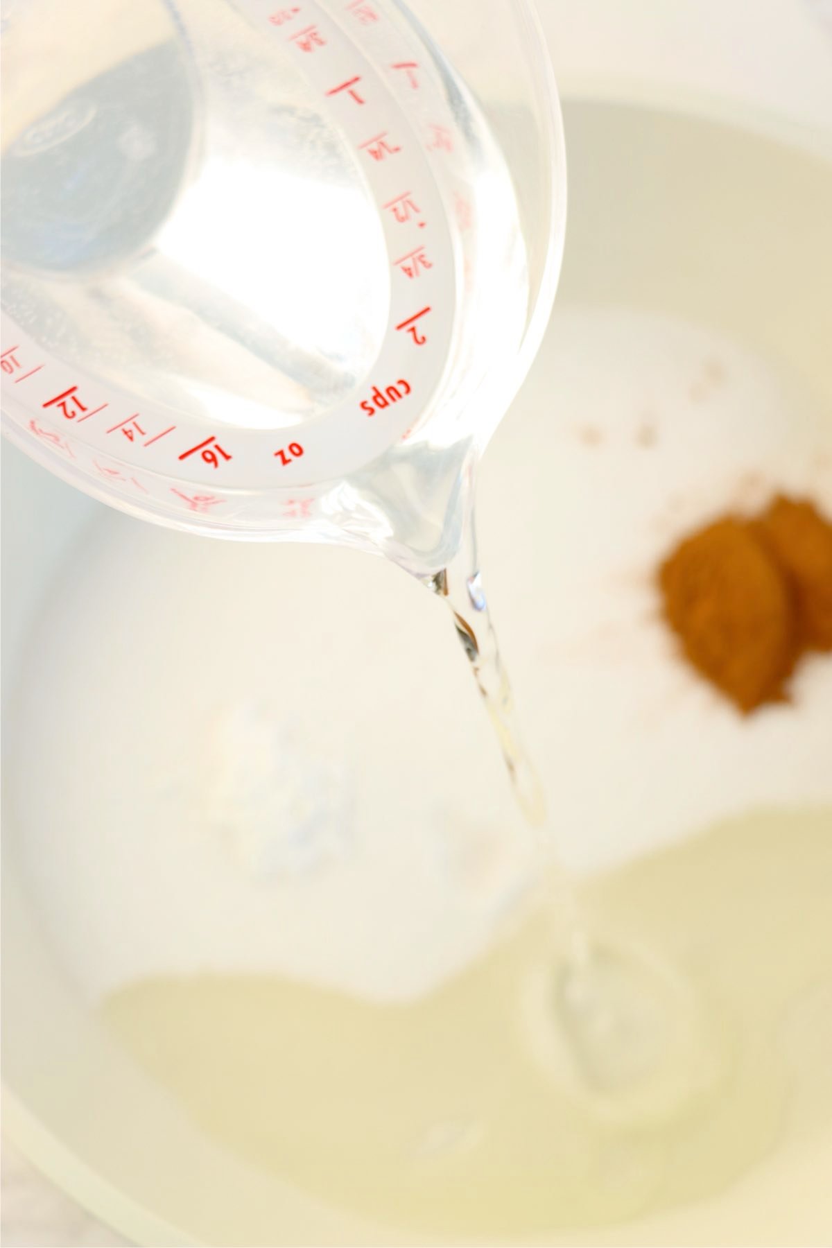 Water being poured into a saucepan with sugar, cornstarch, cinnamon, and lemon juice to make the apple filling base.