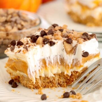A plated slice of the pumpkin dessert showing the graham crust, cream cheese layer, and pumpkin layer.