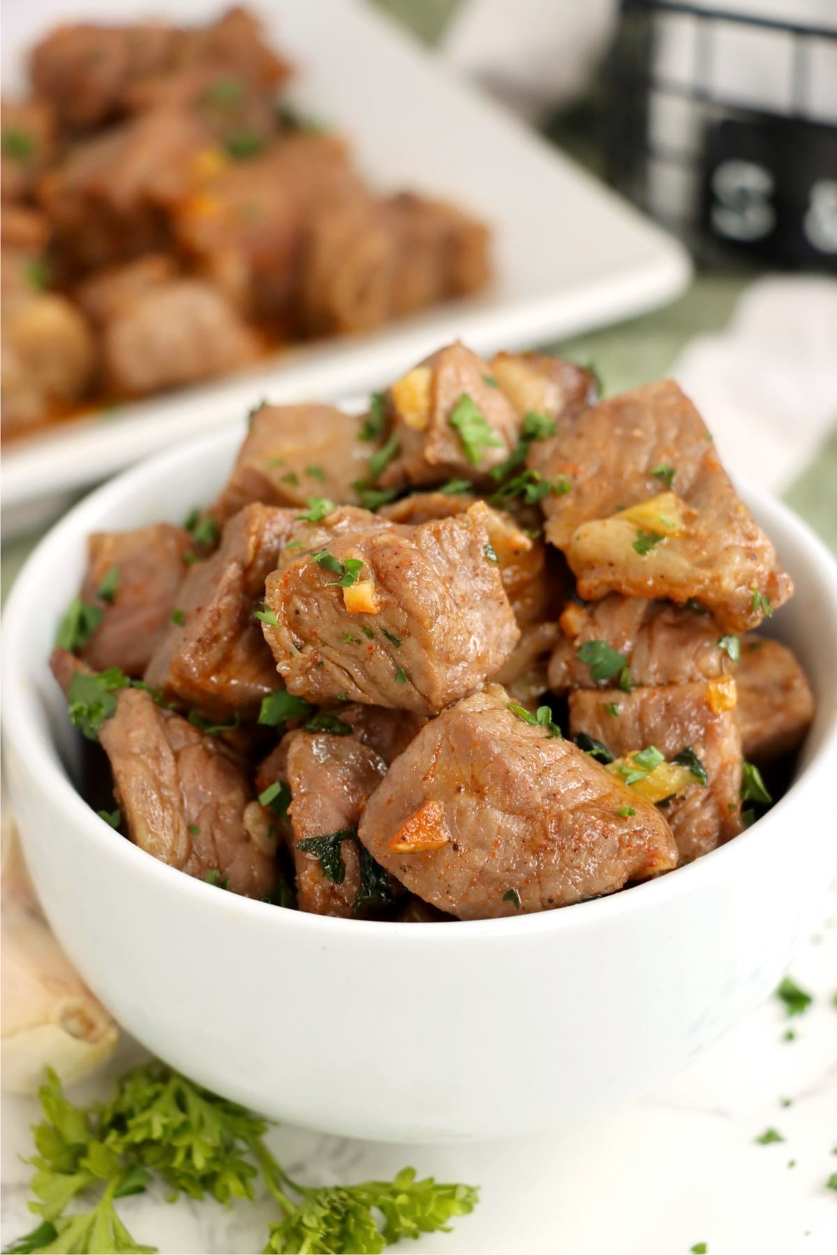 Bowl of juicy air fryer steak bites tossed with garlic butter and fresh parsley.