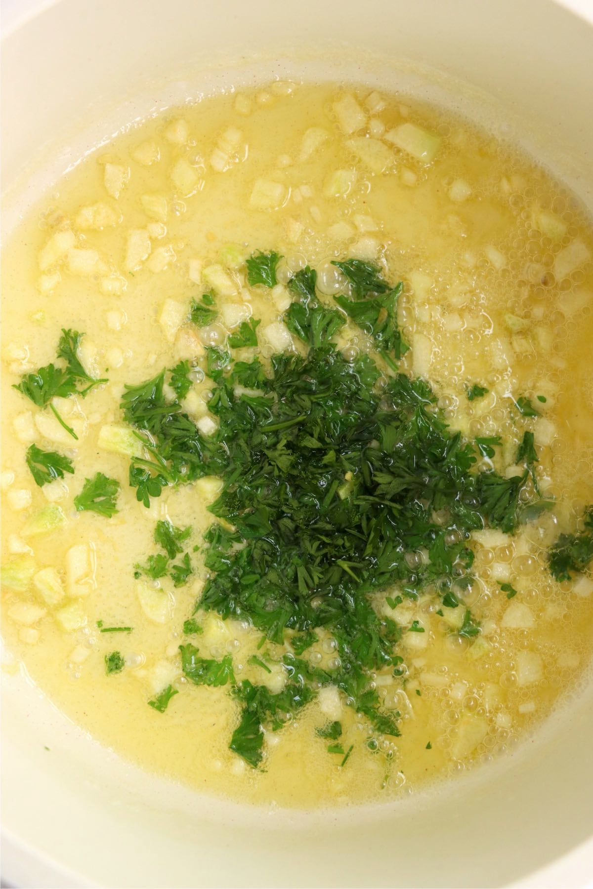 Garlic butter sauce with fresh chopped parsley added, gently simmering.