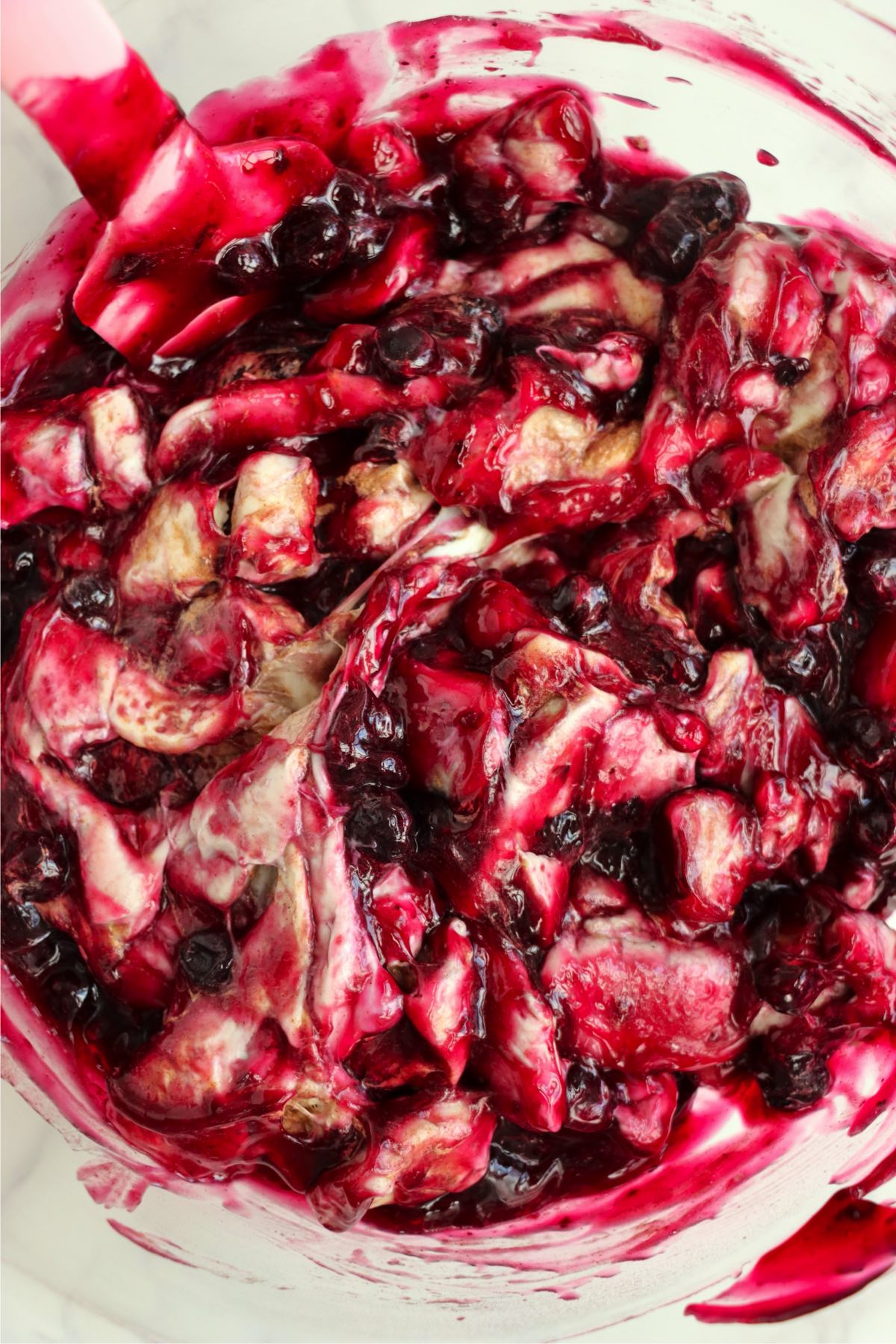 Blueberry pie filling mixed with chopped cinnamon rolls in a bowl.