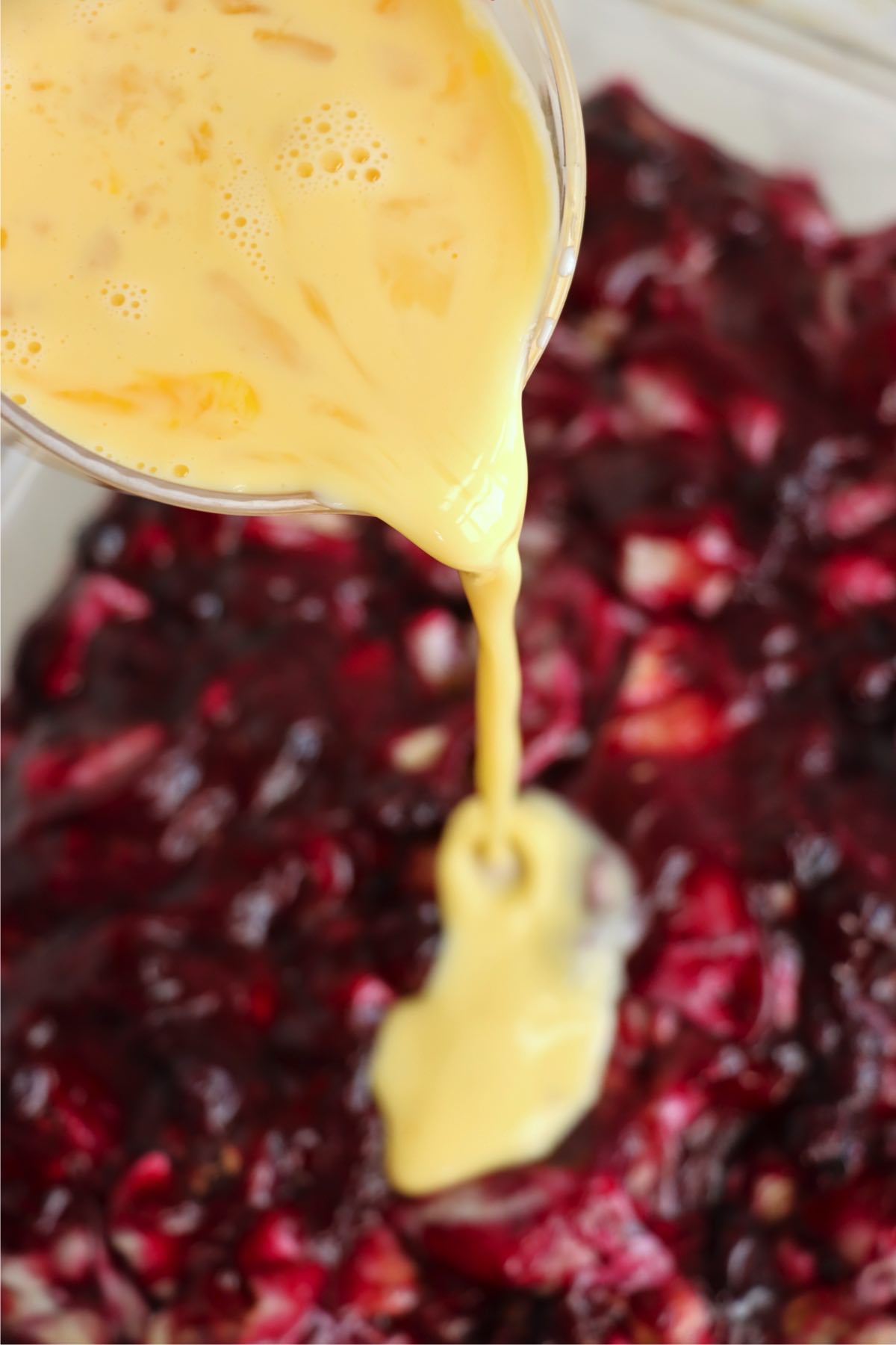 Egg and evaporated milk mixture being poured over the blueberry mixture.