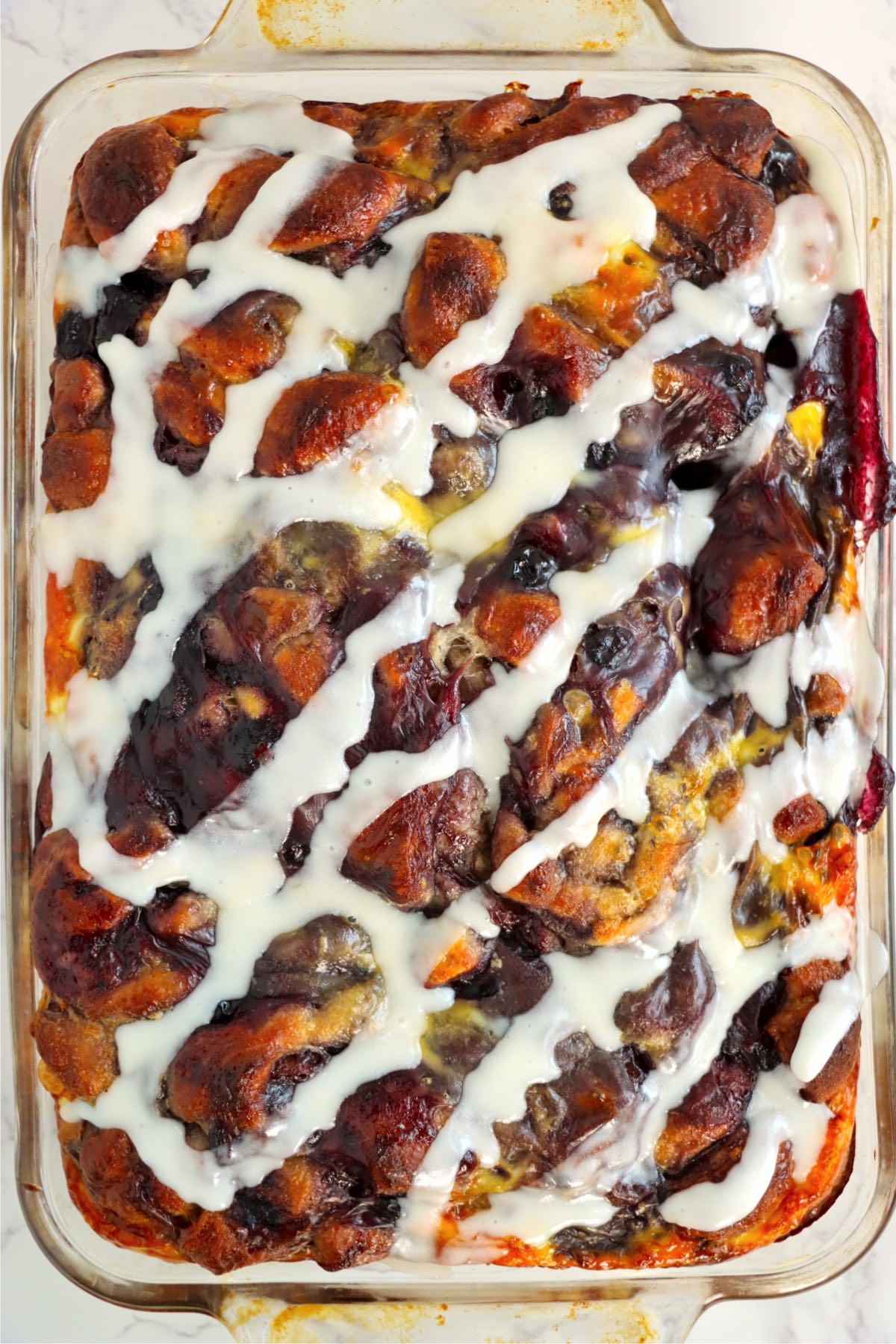 Baked cinnamon roll casserole drizzled with white icing.