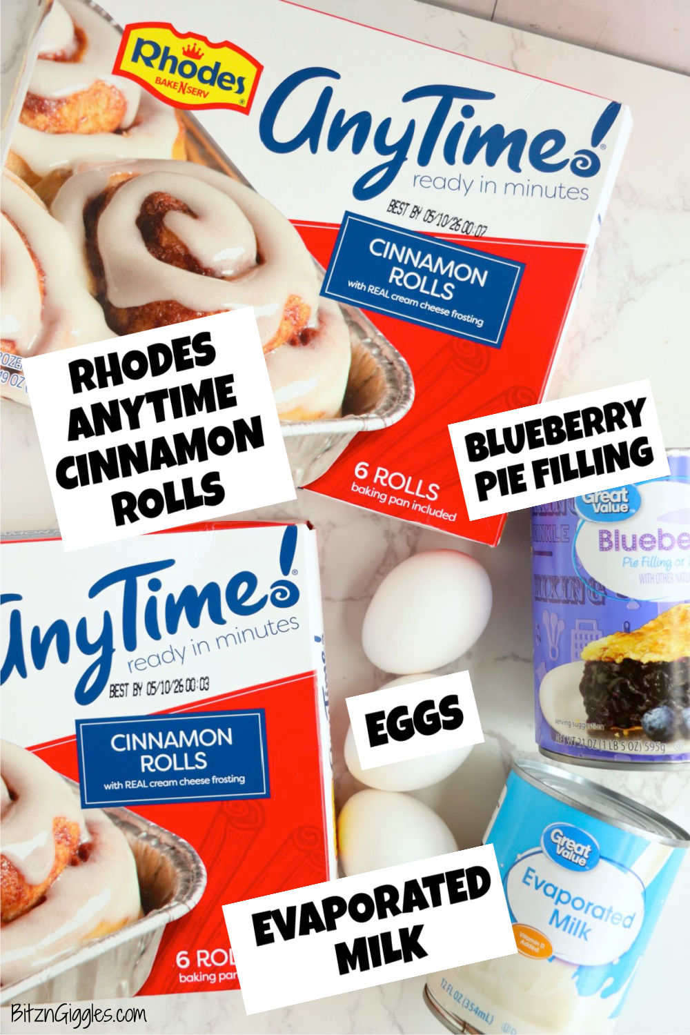 Ingredients displayed together on a white marble surface, including Rhodes cinnamon rolls, blueberry pie filling, eggs, and evaporated milk.