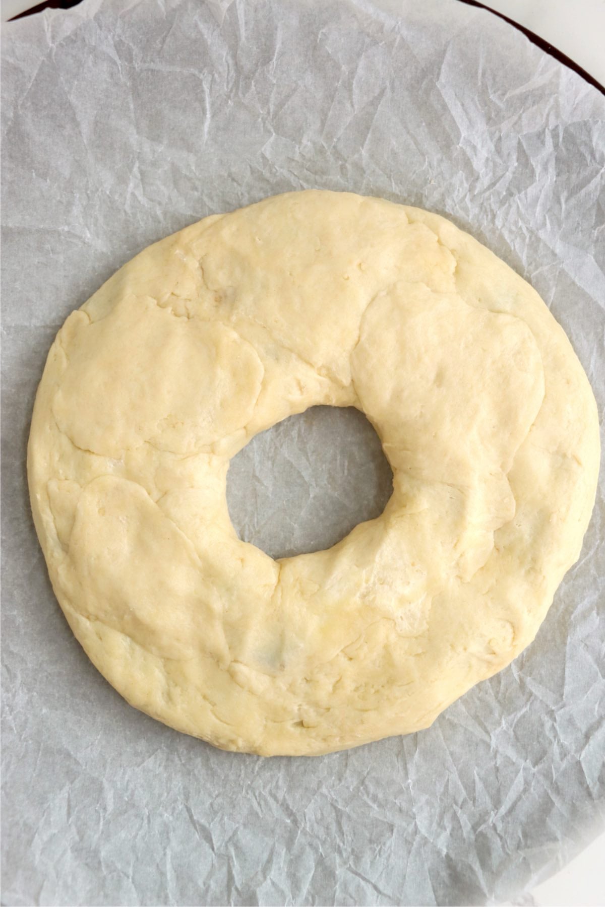 Pastry dough shaped into a circle with an open center on a baking sheet.