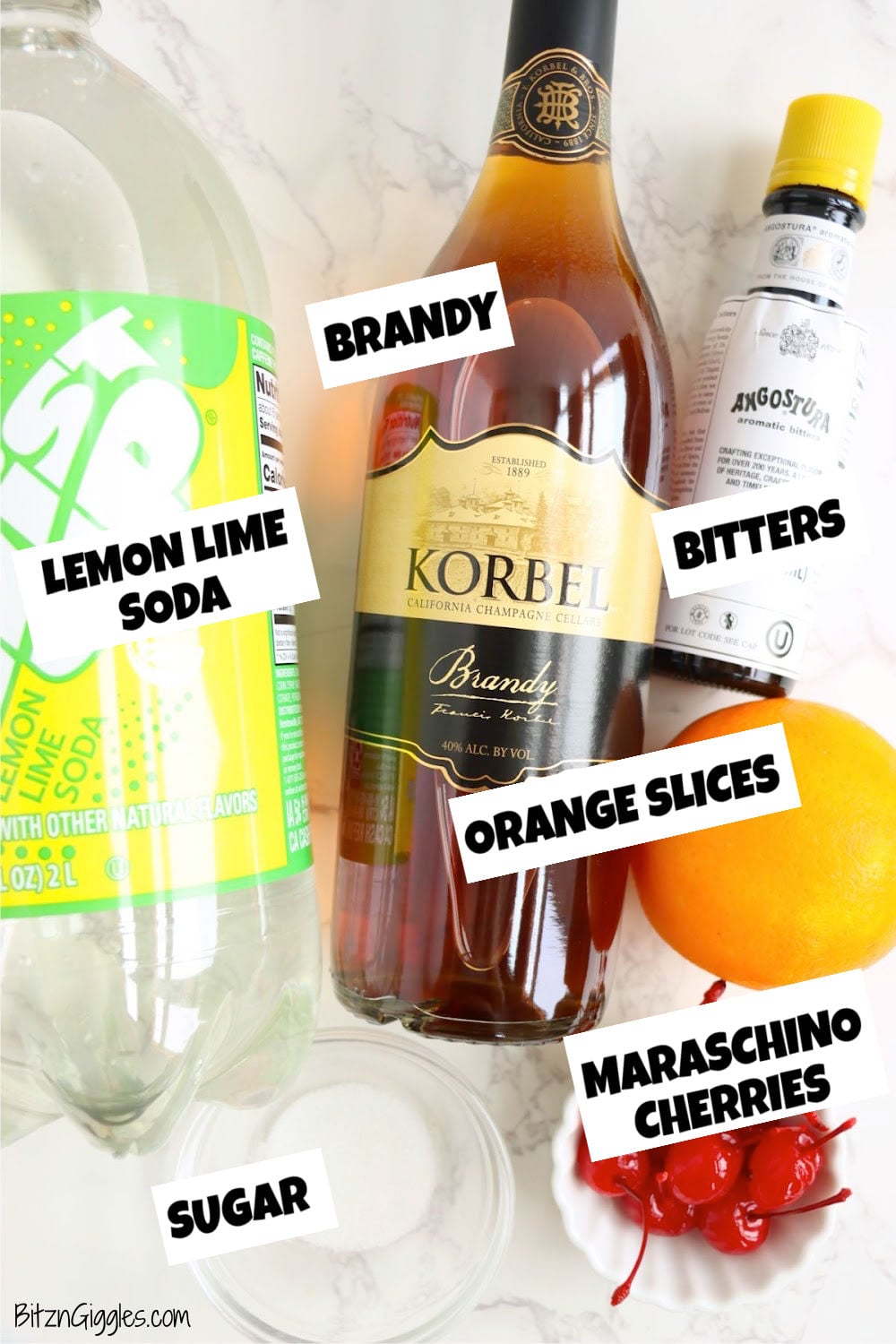 Korbel brandy, lemon-lime soda, Angostura bitters, orange slices, maraschino cherries, and sugar arranged on a marble surface.