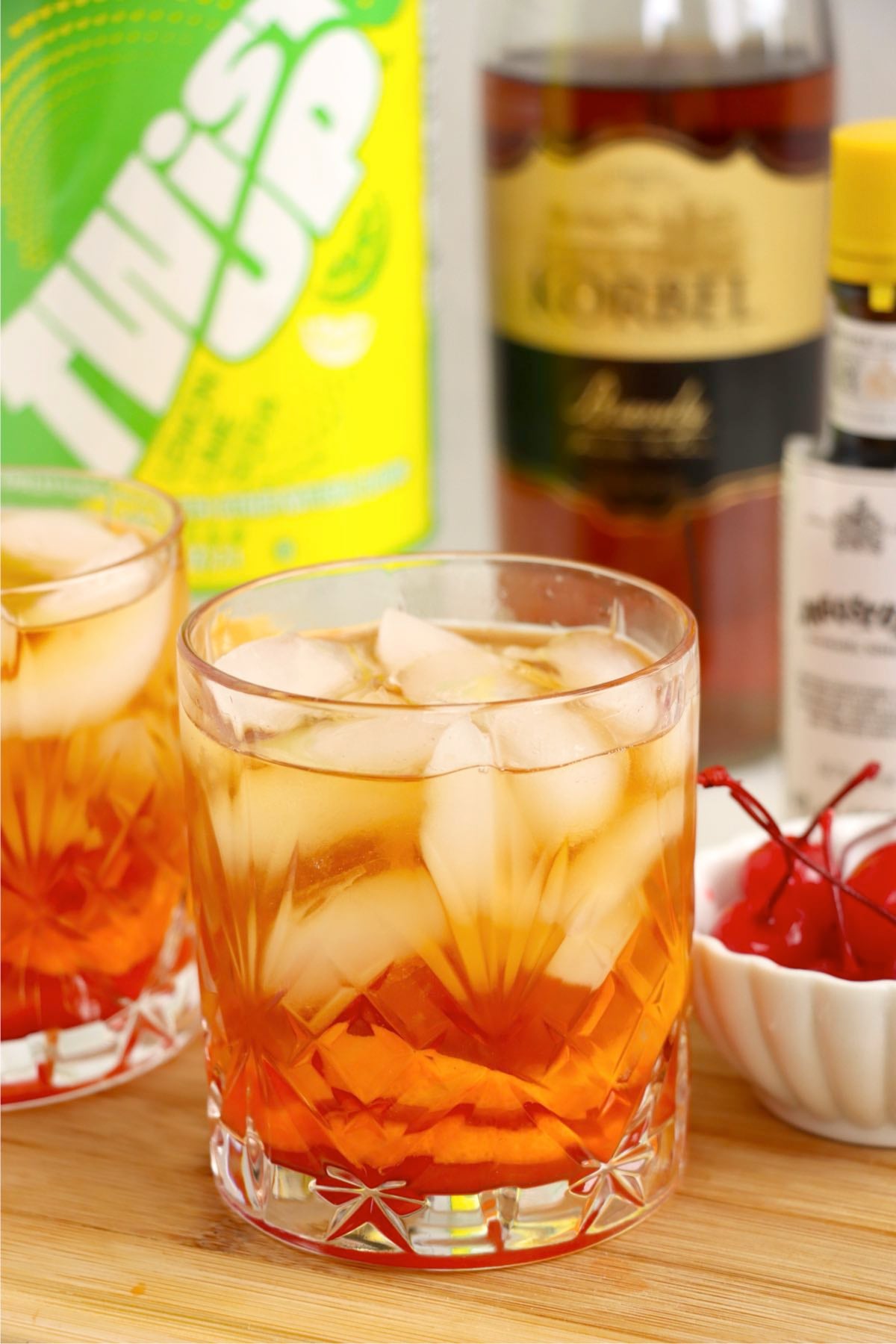 A Wisconsin Old Fashioned cocktail with brandy and soda bottles behind the glass.