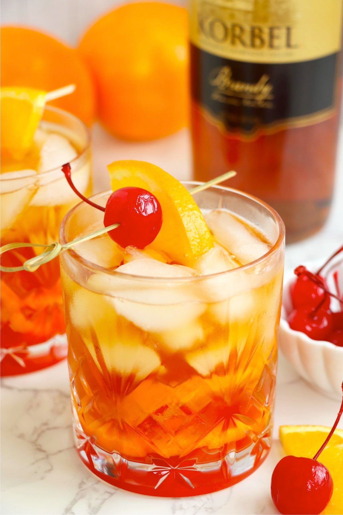 Wisconsin Old Fashioned cocktail showing ice cubes, orange slice, cherry, and layered brandy color.