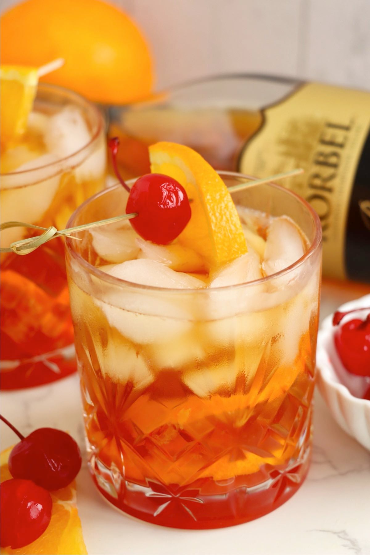 A freshly made Wisconsin Old Fashioned in a cut-glass tumbler with ice, orange slice, and maraschino cherry garnish.