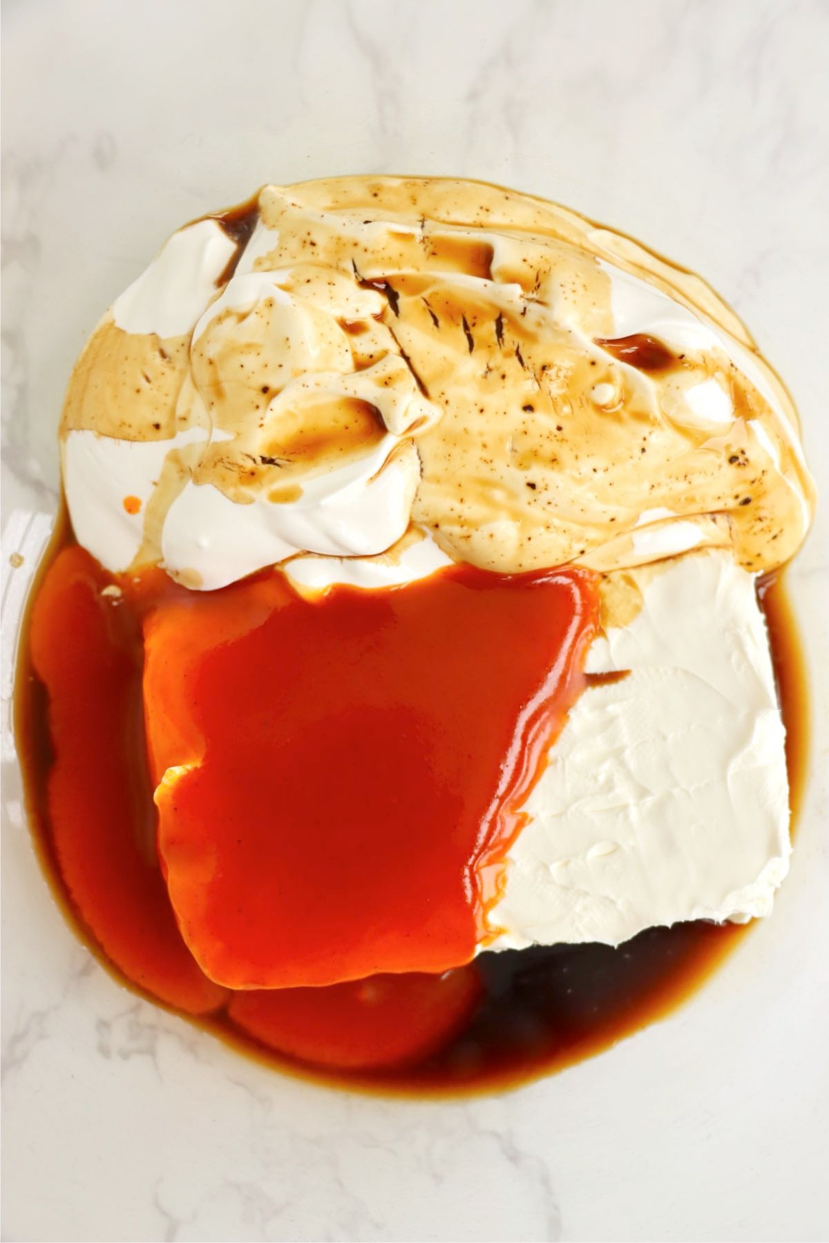 Cream cheese, sour cream, French dressing, Worcestershire sauce, and seasonings partially mixed together in a large white bowl.