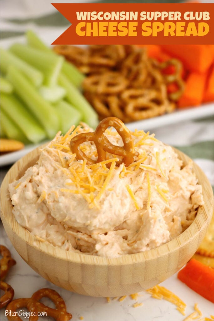 A wooden bowl full of cheese spread and topped with a pretzel.