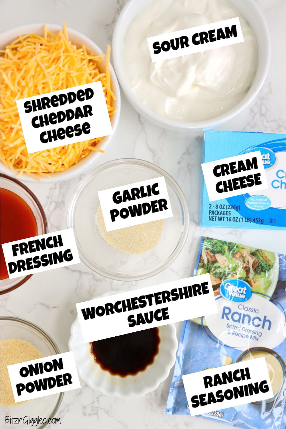 Individual bowls of shredded cheddar cheese, sour cream, cream cheese, French dressing, Worcestershire sauce, garlic powder, onion powder, and ranch seasoning arranged on a countertop.