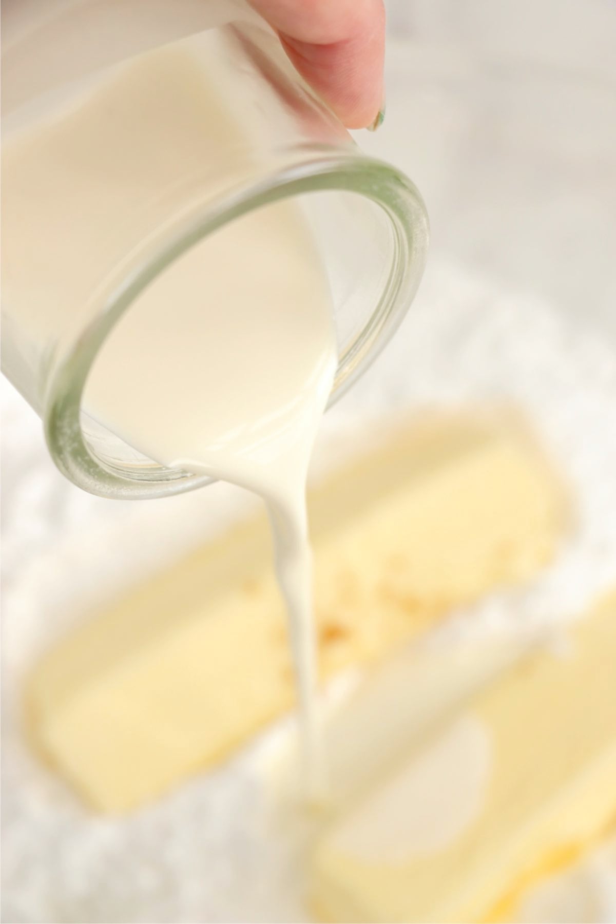 Milk being poured into a mixing bowl with cake ingredients.