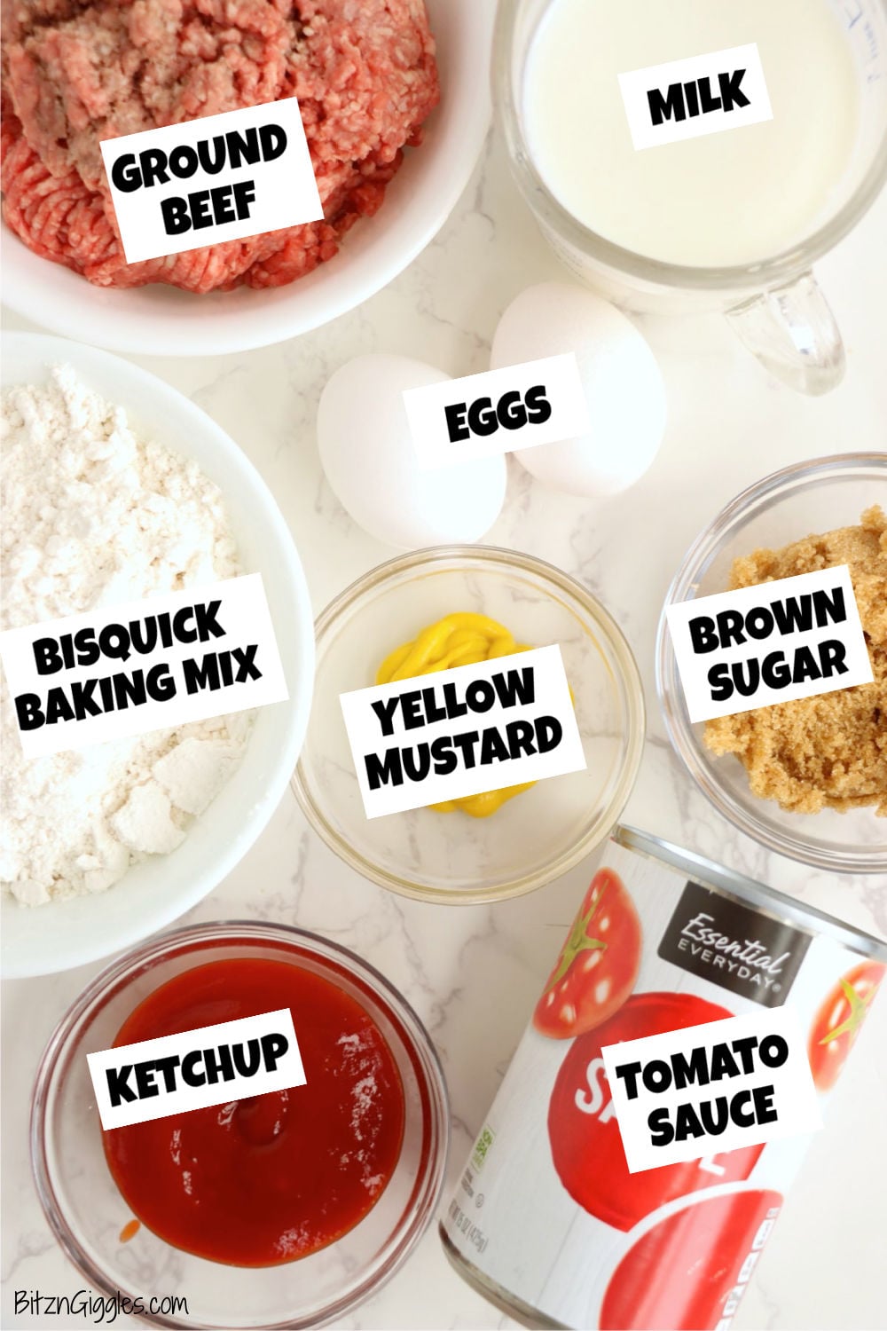 Ingredients for a sloppy joe bake arranged and labeled on a countertop, including ground beef, Bisquick, milk, eggs, ketchup, tomato sauce, mustard, and brown sugar.