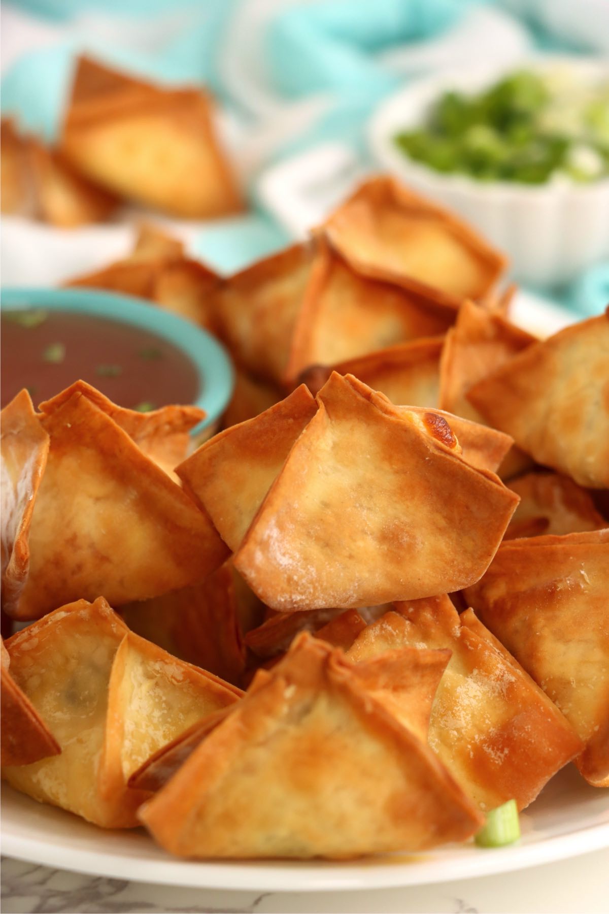 Plate of golden brown air fryer crab rangoons with dipping sauce.