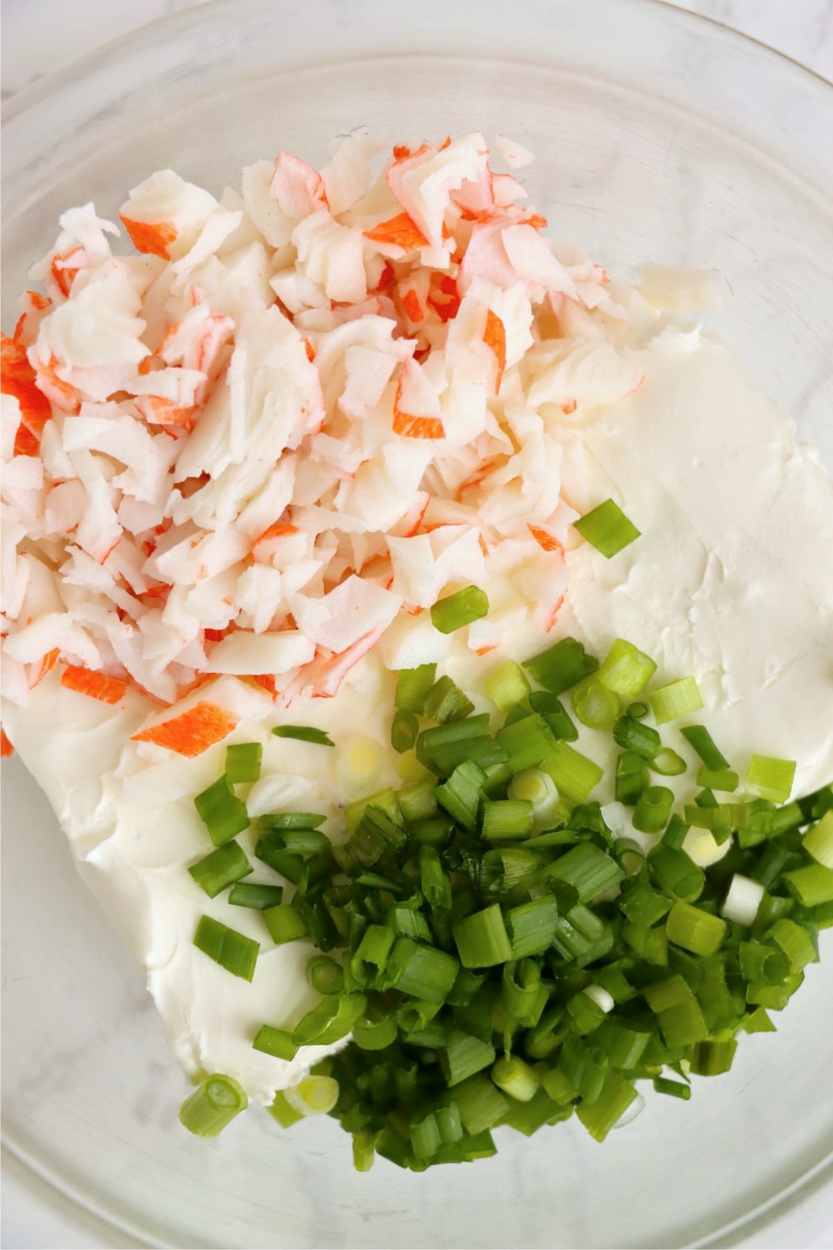 Cream cheese, chopped imitation crab meat, and green onions combined in a mixing bowl.