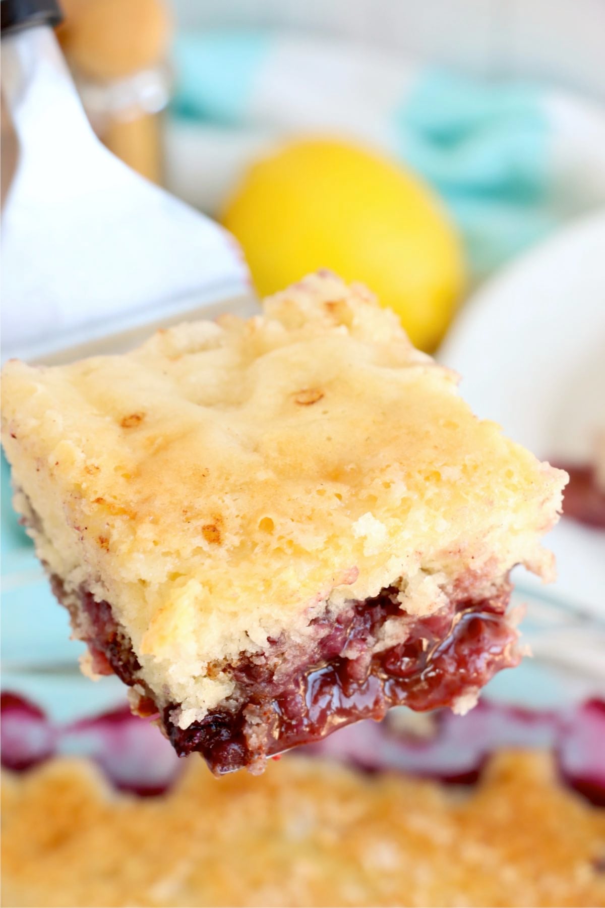 A square of blueberry pudding cake lifted from the dish revealing the soft cake and fruit base.