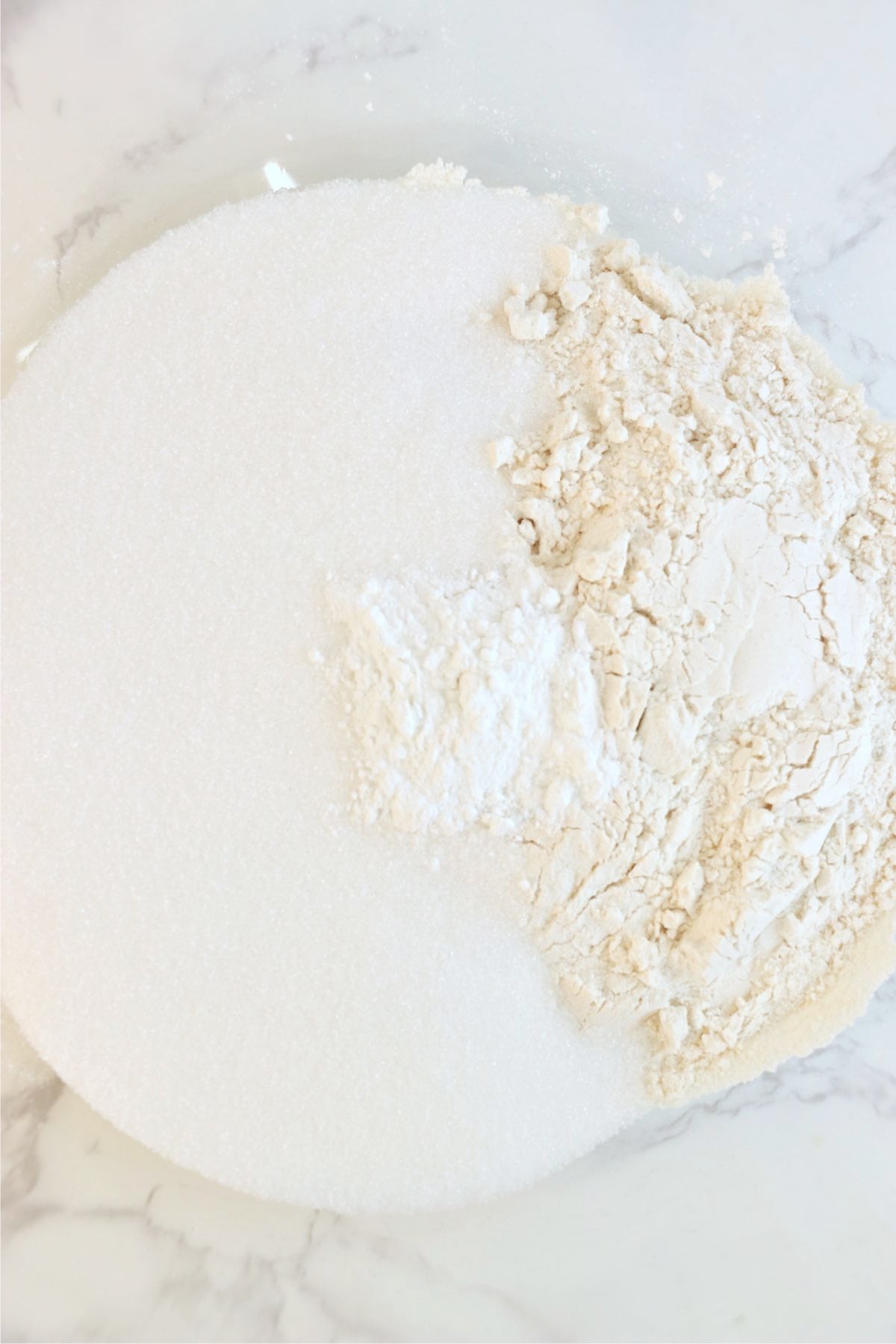 Granulated sugar, flour, baking powder, and salt measured together in a mixing bowl.