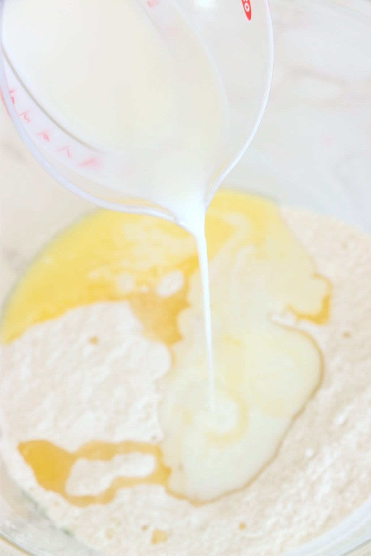 Whole milk being poured into dry ingredients to form a cake batter.