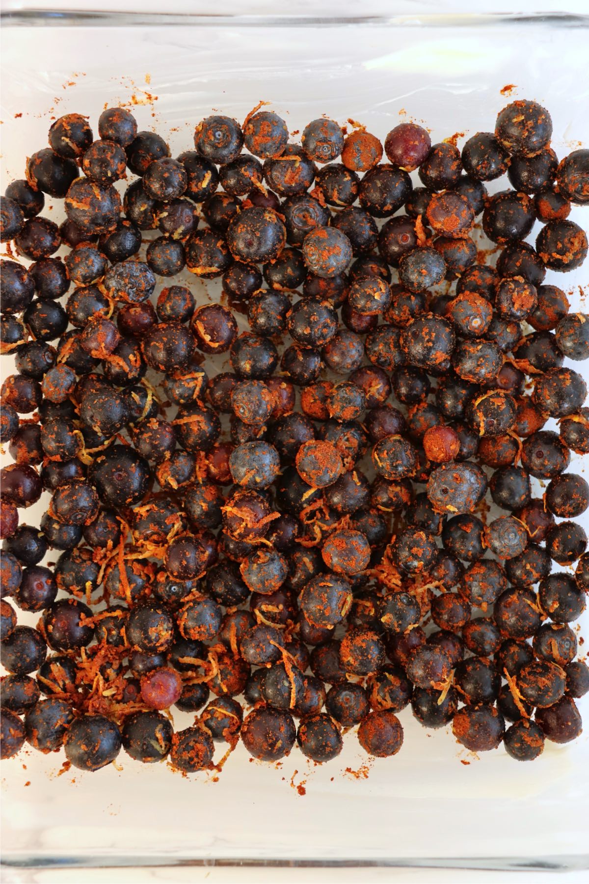 Spiced blueberries spread evenly across the bottom of a greased baking dish.