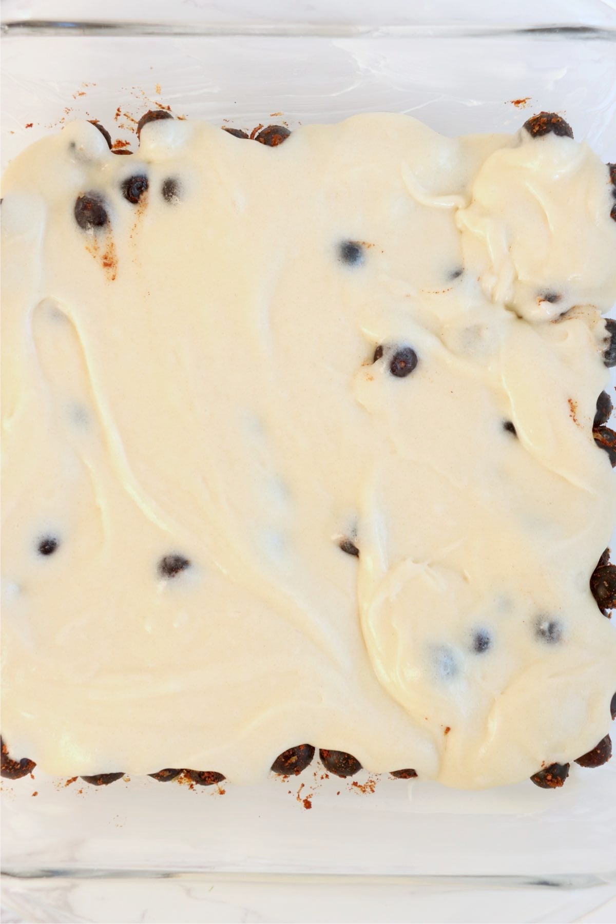 Cake batter poured over blueberries and smoothed across the baking dish.