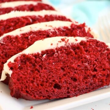 Red velvet loaf cake sliced on a white platter.