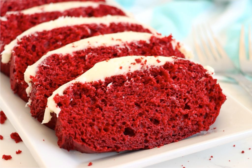 Red velvet loaf cake sliced on a white platter.