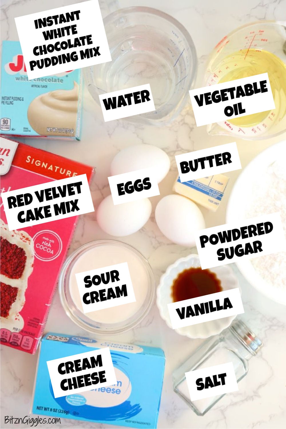 Ingredients for red velvet loaf cake and cream cheese frosting on a marble countertop.
