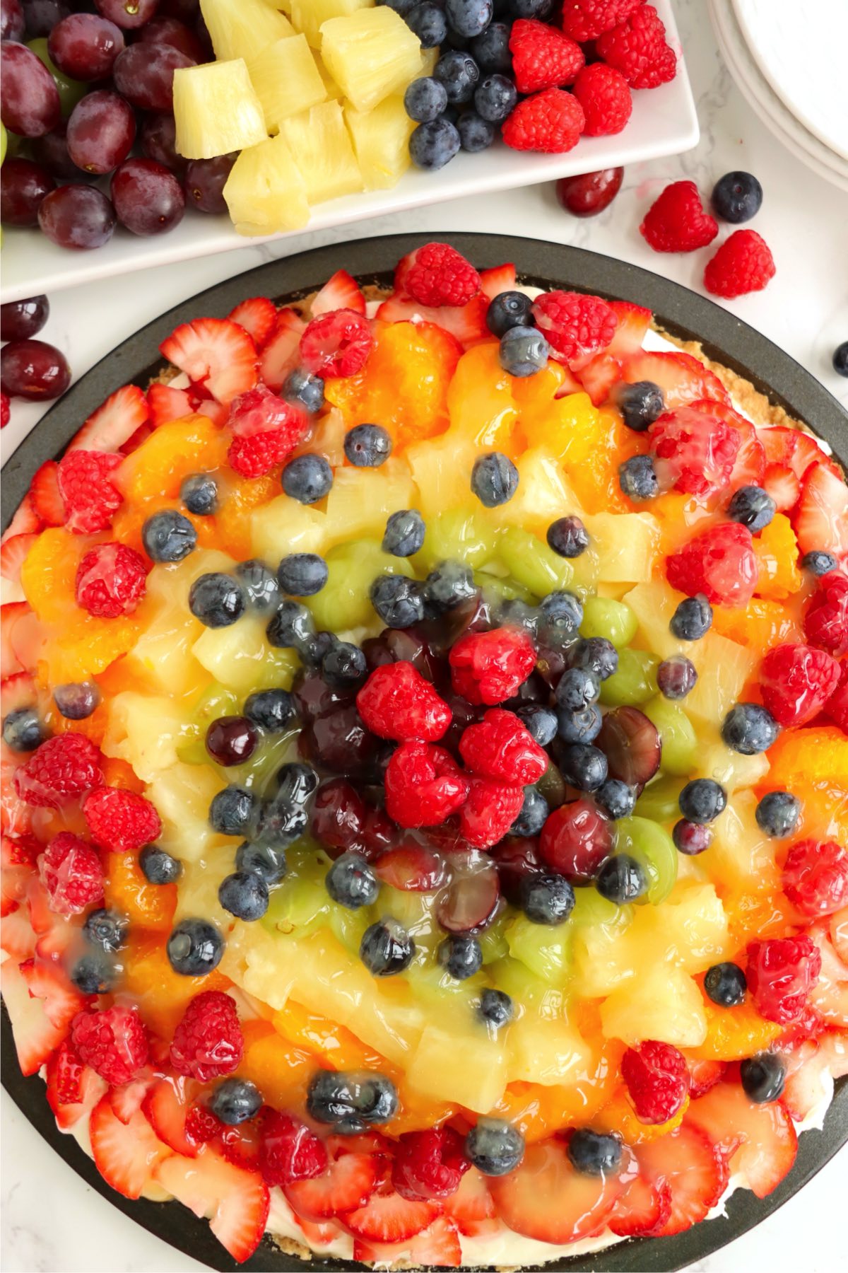 Fully assembled fruit tart with a glossy glaze over colorful fresh fruit.