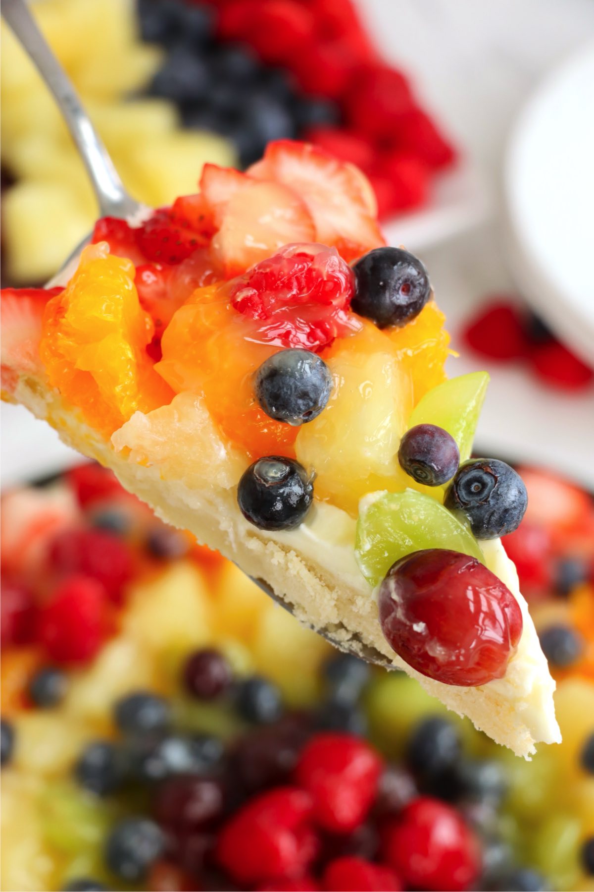 A fruit tart slice being lifted on a spatula.