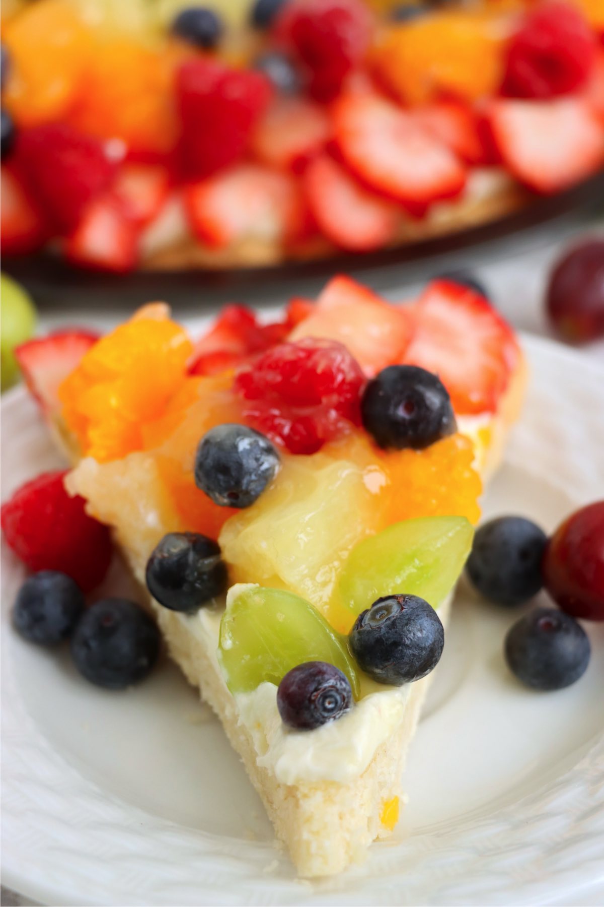 Fruit tart slice with fork showing creamy filling and crust.