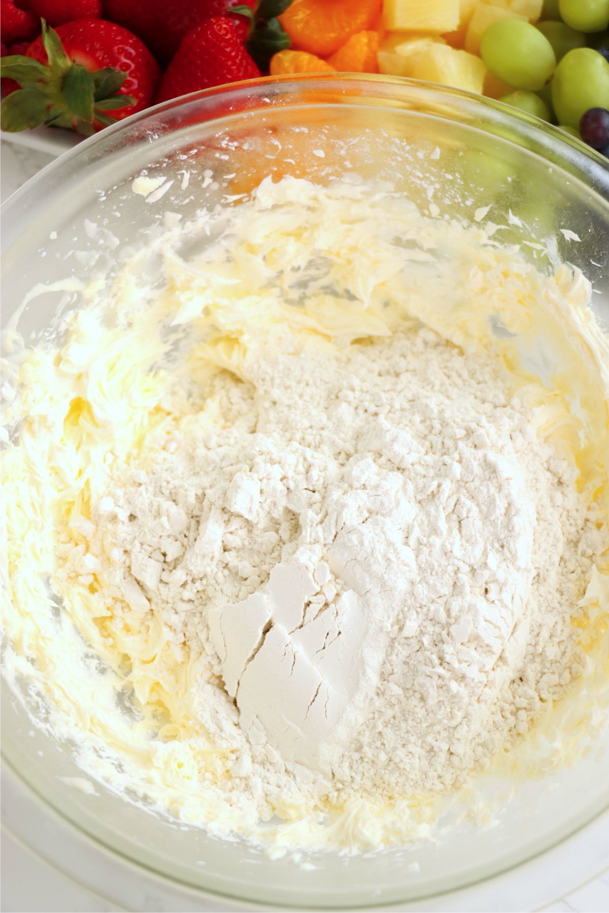 Creamed butter mixture with flour added in a glass bowl for making the tart crust dough.