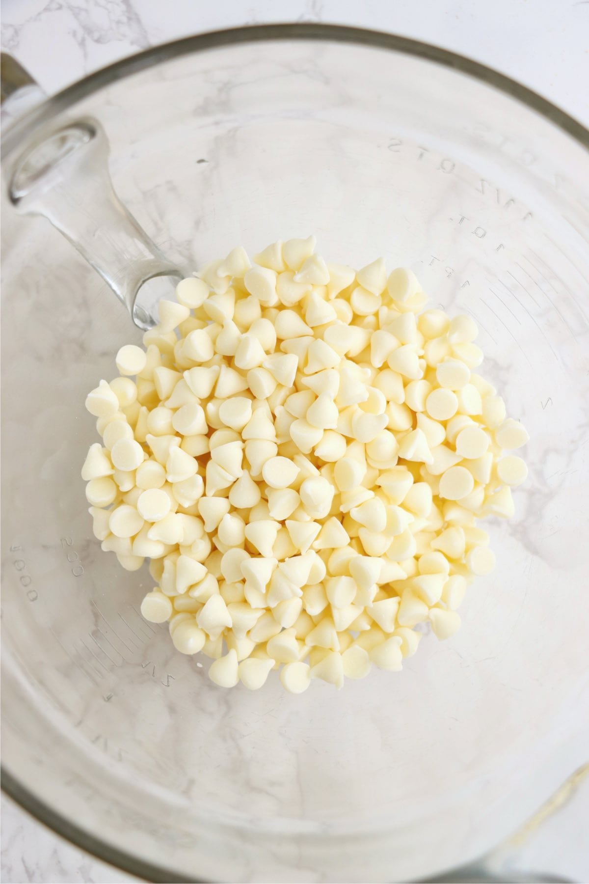 White chocolate chips in a measuring cup ready to be melted.
