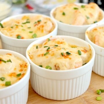 Baked Coquilles St. Jacques in ramekins with golden tops and green onions.