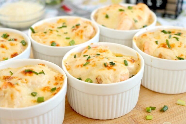Baked Coquilles St. Jacques in ramekins with golden tops and green onions.