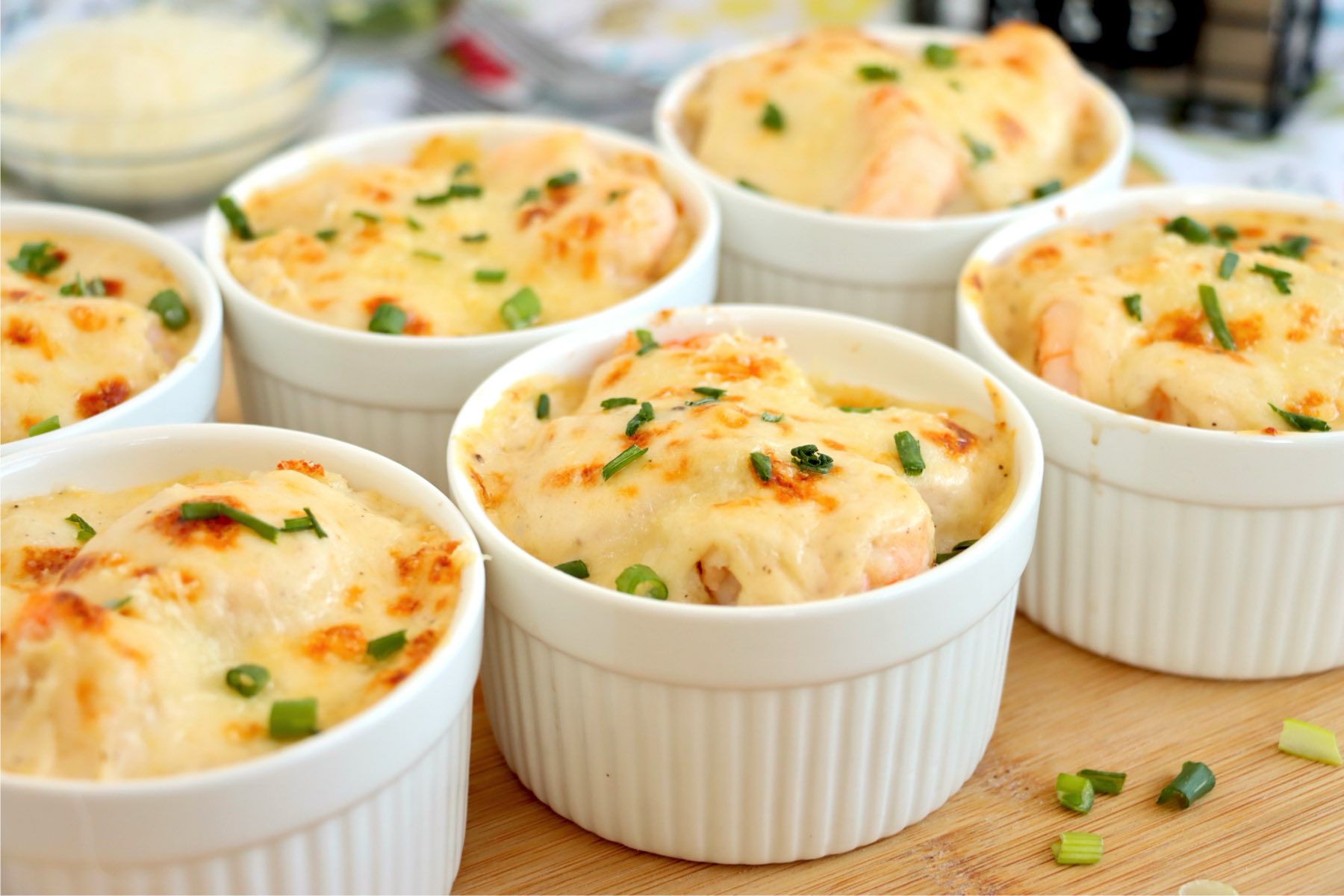 Baked Coquilles St. Jacques in ramekins with golden tops and green onions.