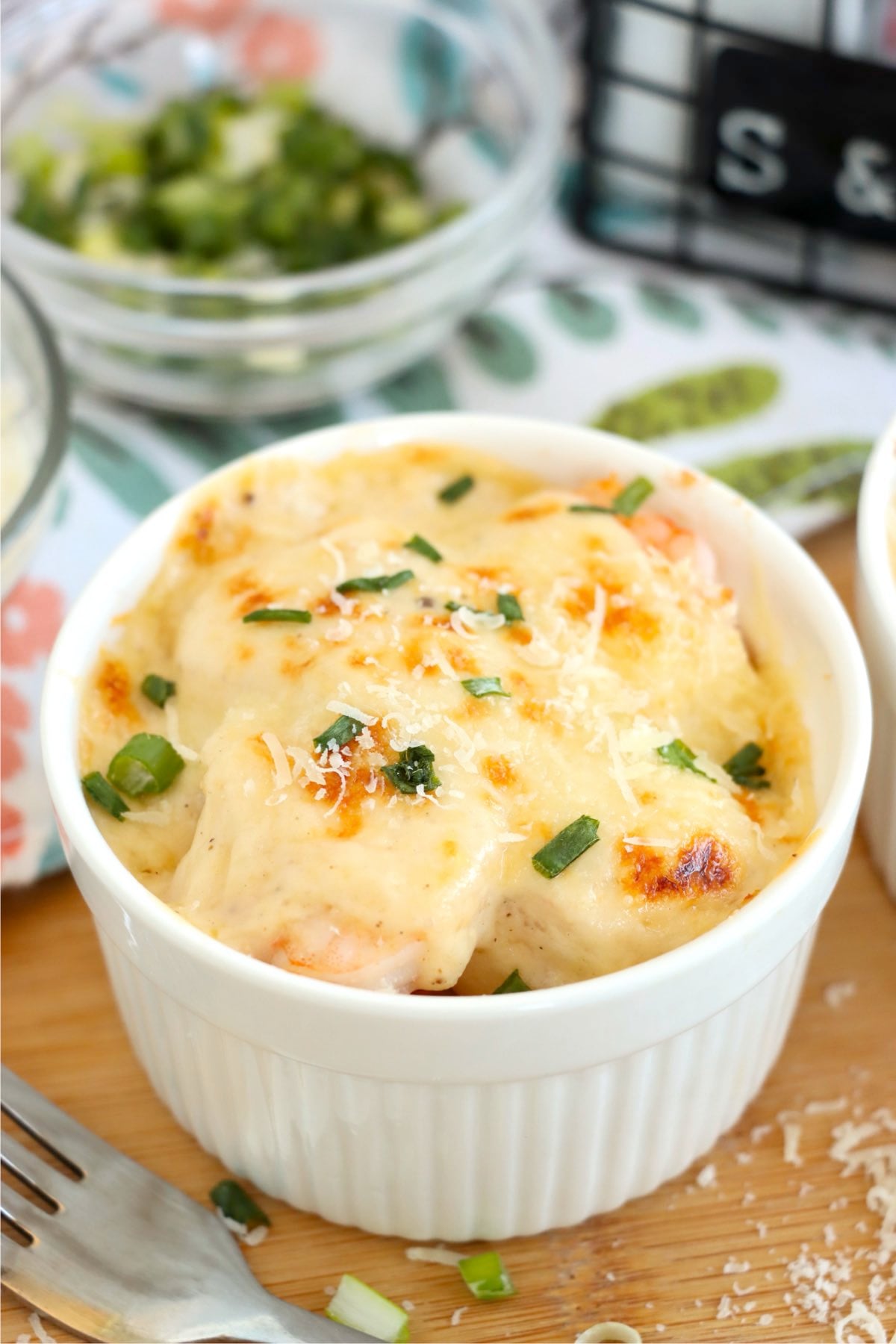 Baked Coquilles St. Jacques in a white ramekin with creamy seafood sauce.