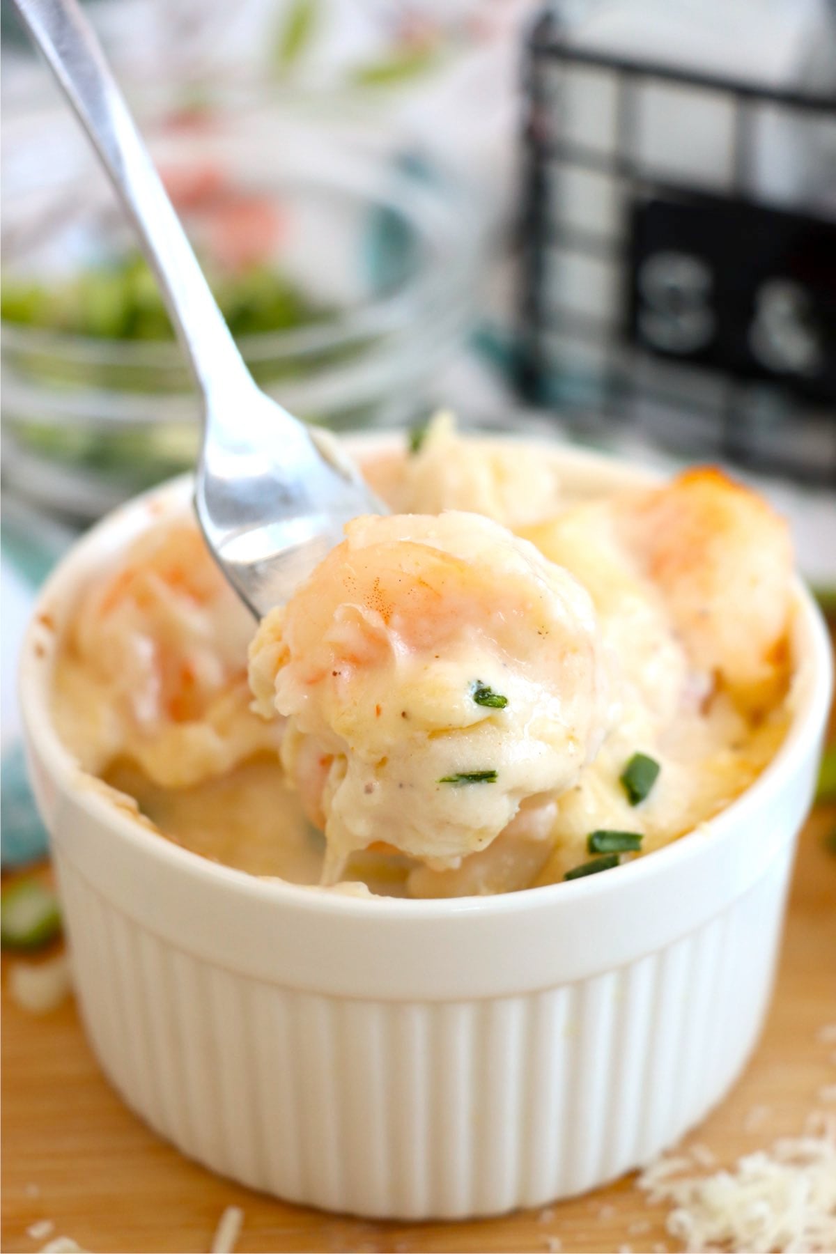 Fork lifting a bite of creamy shrimp and scallops from baked Coquilles St. Jacques.
