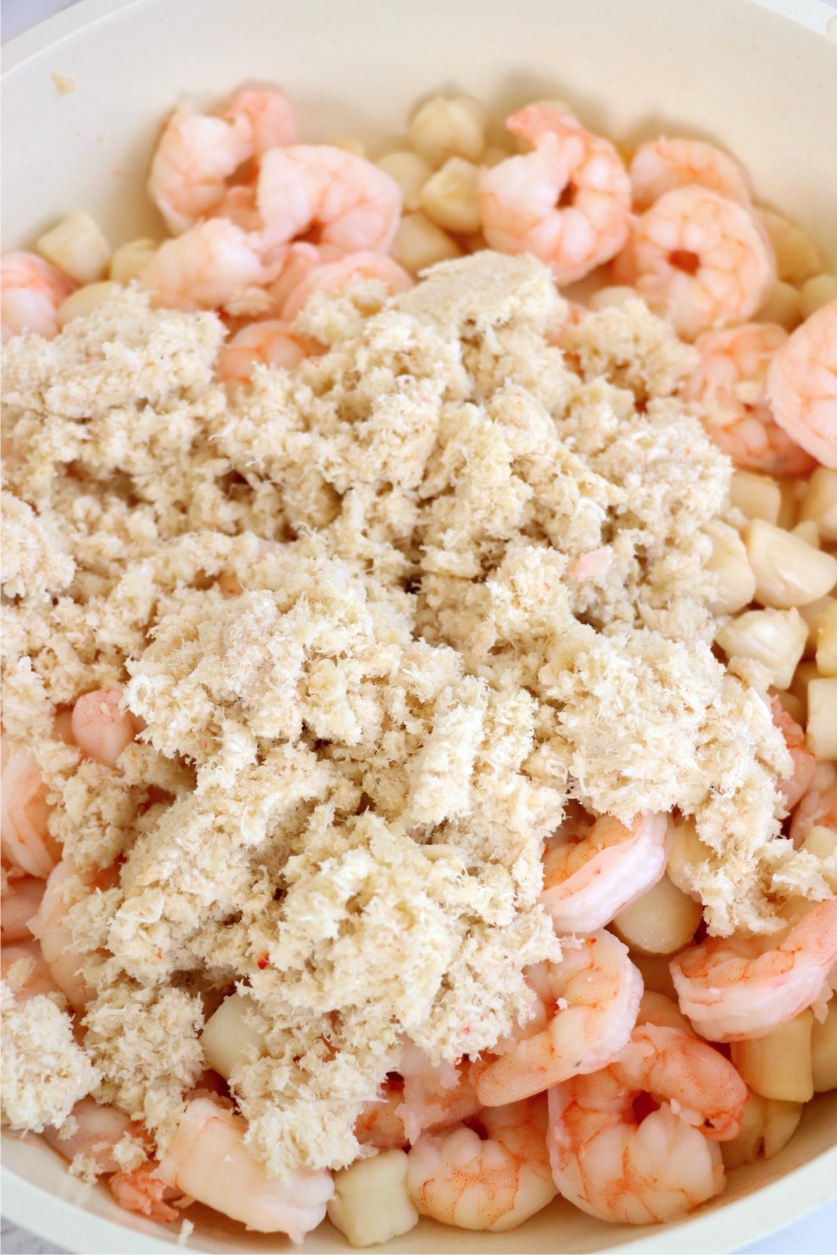 Cooked shrimp, scallops, and crab meat combined in a bowl for Coquilles St. Jacques.