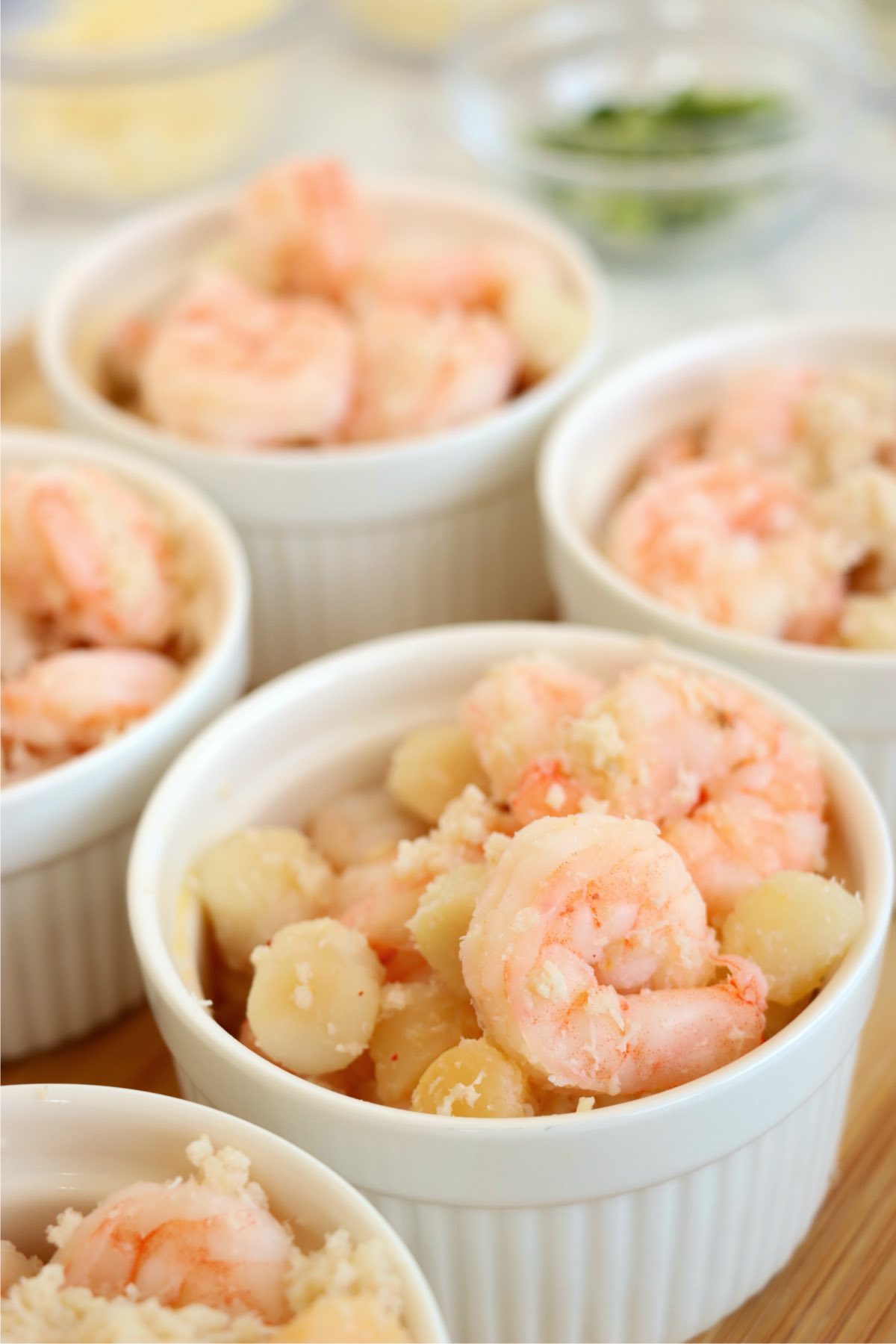 Shrimp and scallops portioned into white ramekins for baked Coquilles St. Jacques.