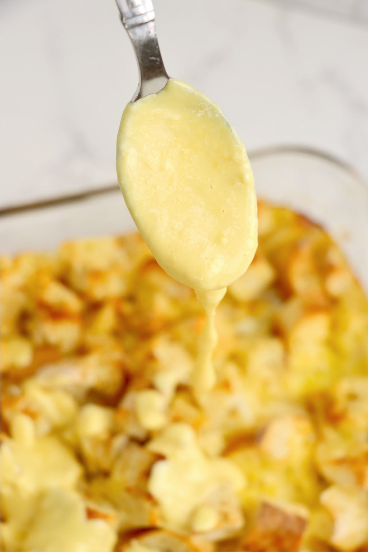 Creamy homemade hollandaise sauce drizzled from a spoon.