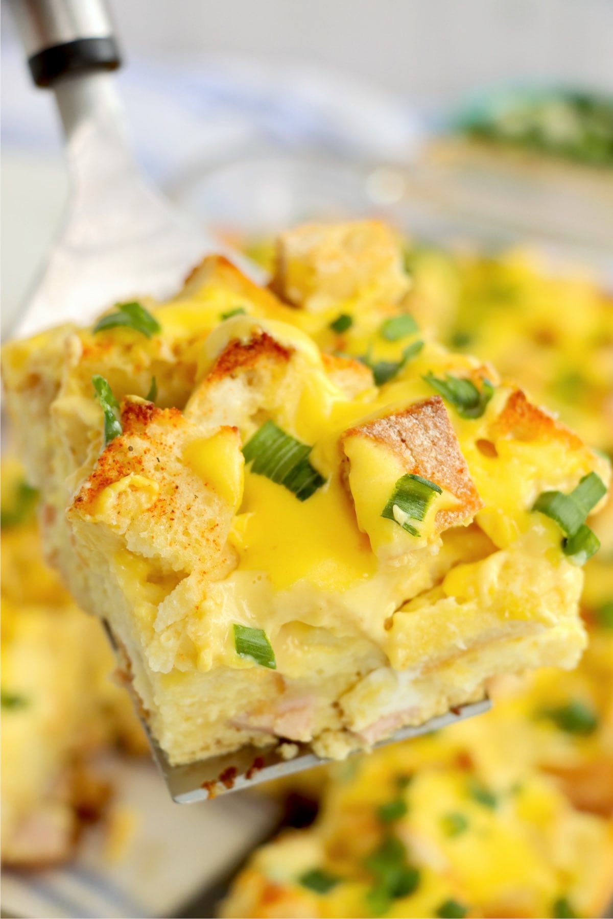 A slice of eggs Benedict casserole lifted from the baking dish.