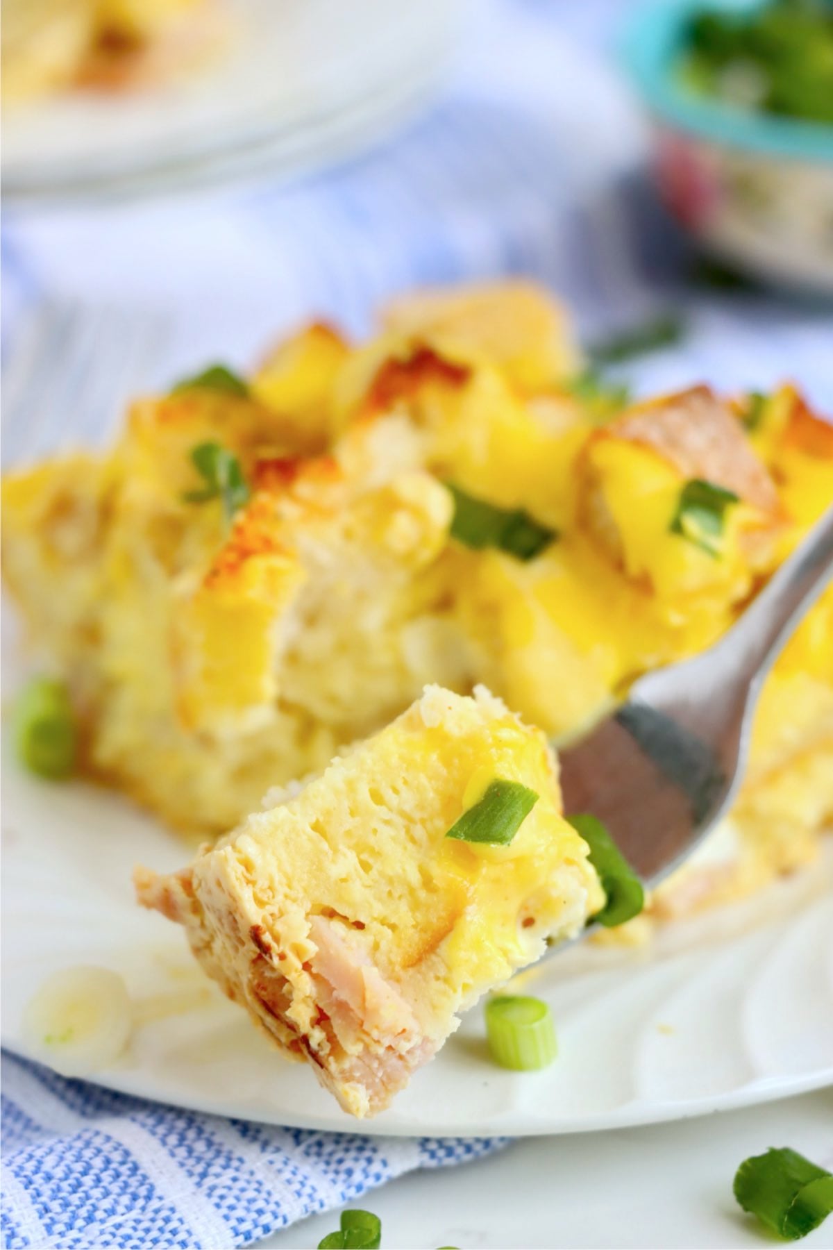 Fork holding a piece of eggs Benedict casserole.