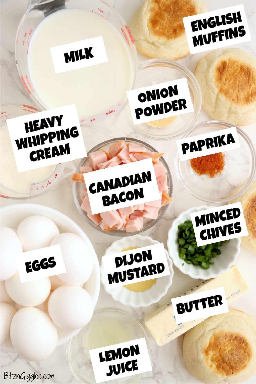 Eggs Benedict casserole ingredients arranged on a countertop with eggs, English muffins, Canadian bacon, and hollandaise ingredients.