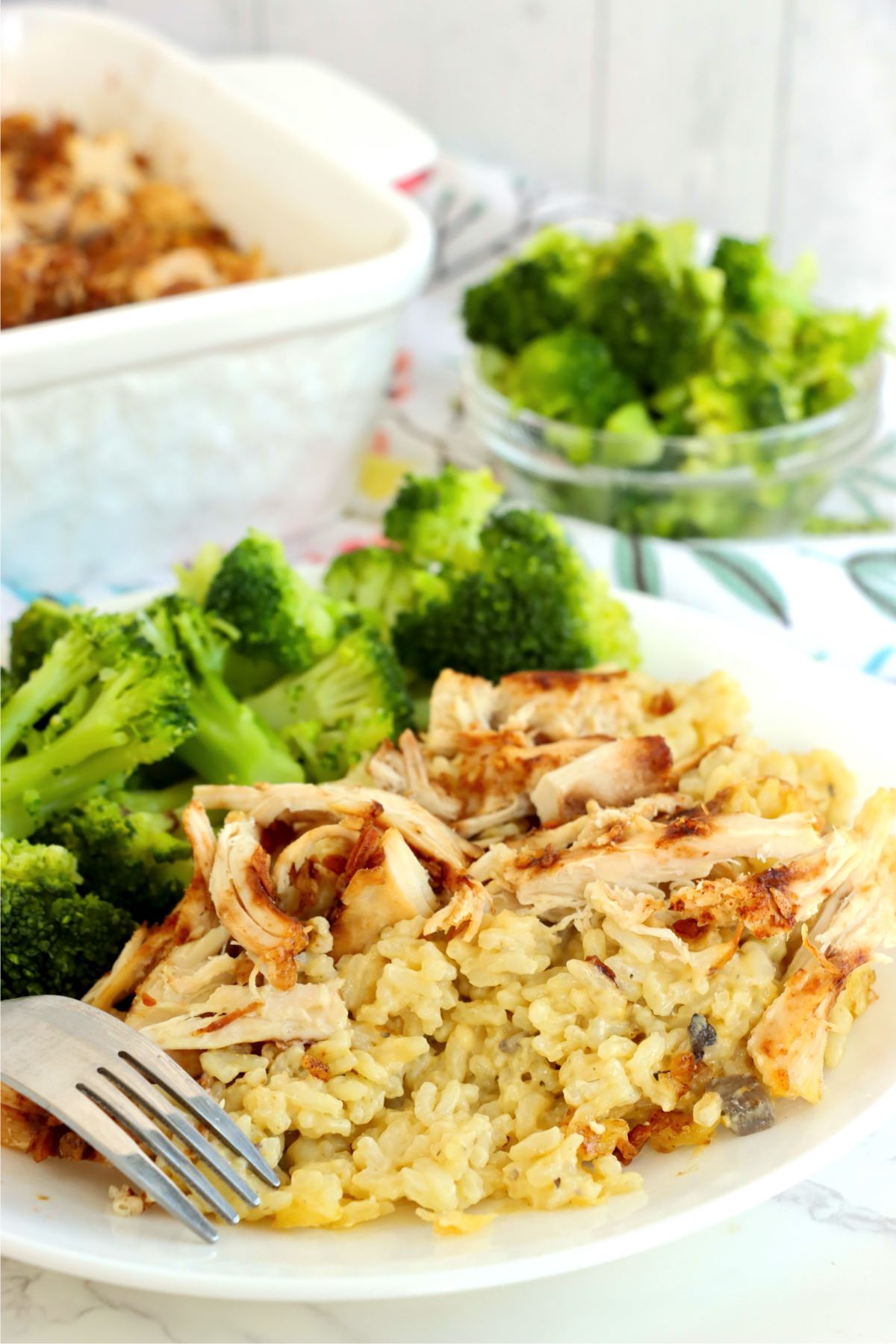 Plate of onion soup mix chicken and rice casserole served with steamed broccoli and a fork.