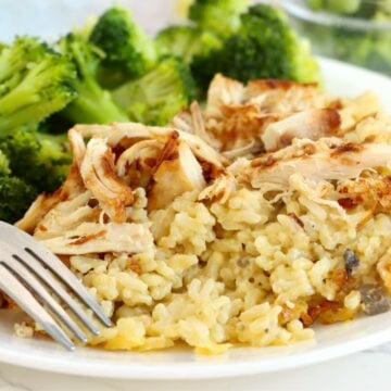 Creamy chicken and rice casserole served on a white plate with steamed broccoli and casserole dish in the background.