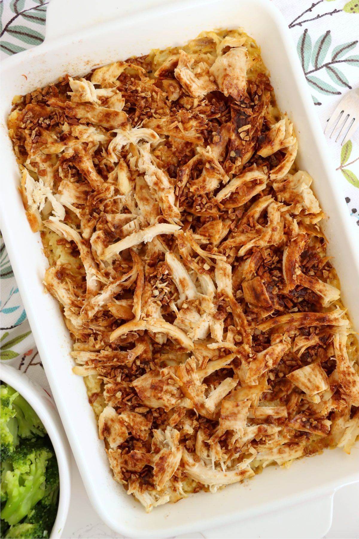 Baked chicken and rice casserole with browned chicken and onion topping in a white baking dish.
