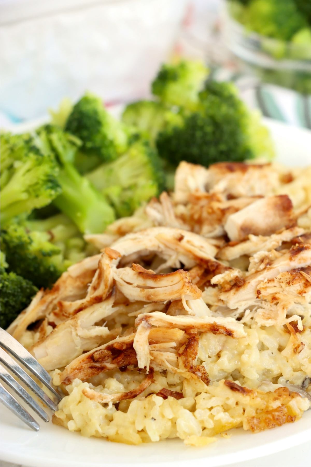 Plate of onion soup mix chicken and rice casserole served with steamed broccoli and a fork.