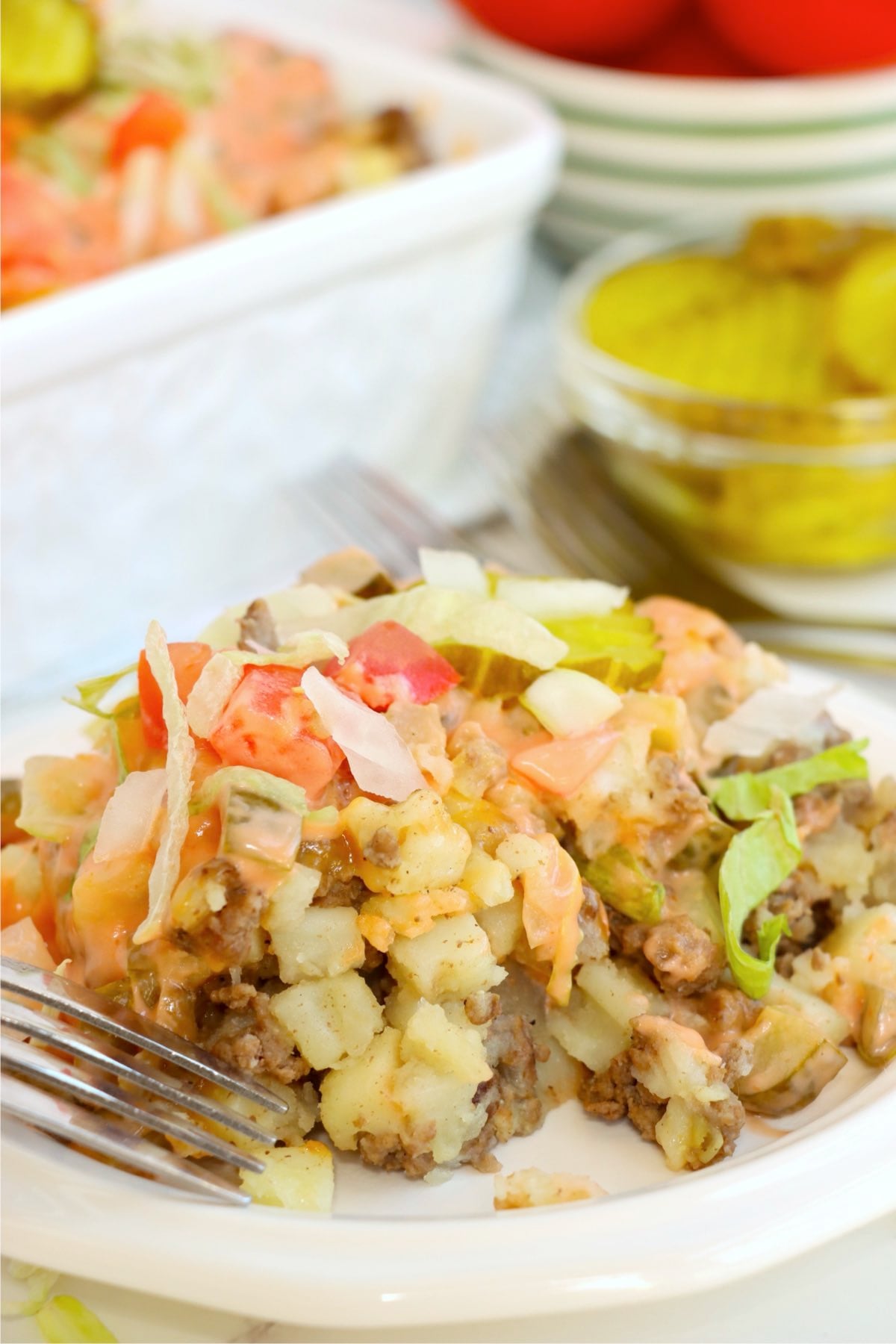 Plated casserole with lettuce, tomato, and pickles.